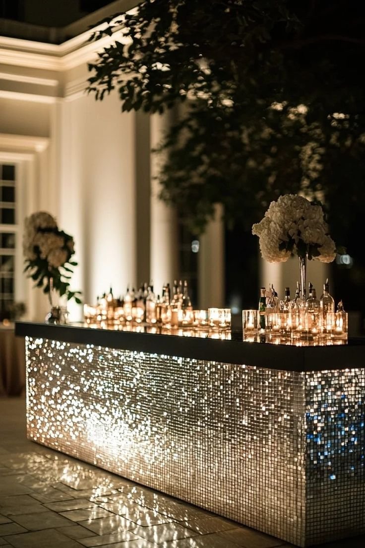 A candlelit mirrored event bar with white floral arrangements